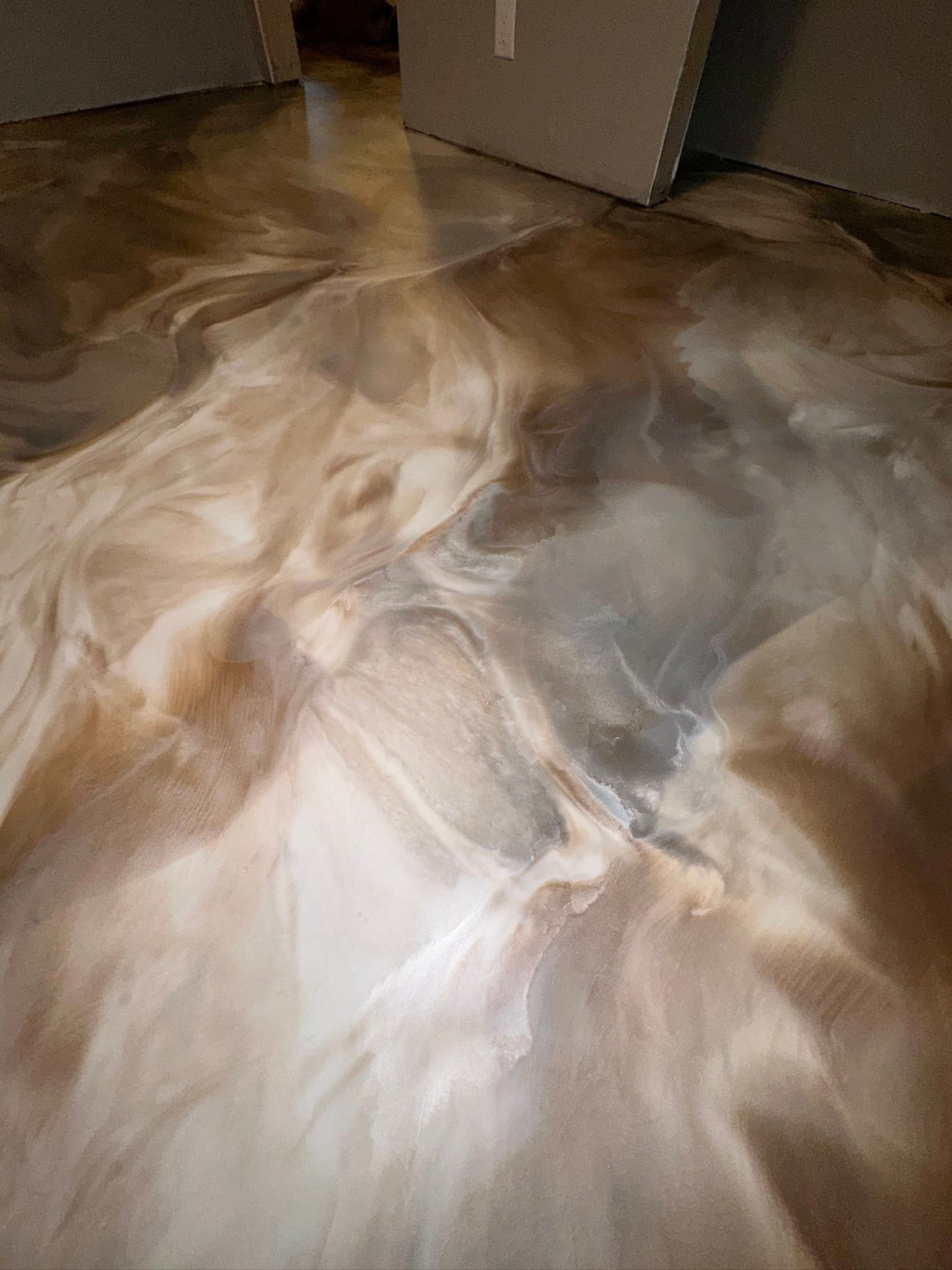 Metallic epoxy flooring with swirling gold, silver, and brown tones.