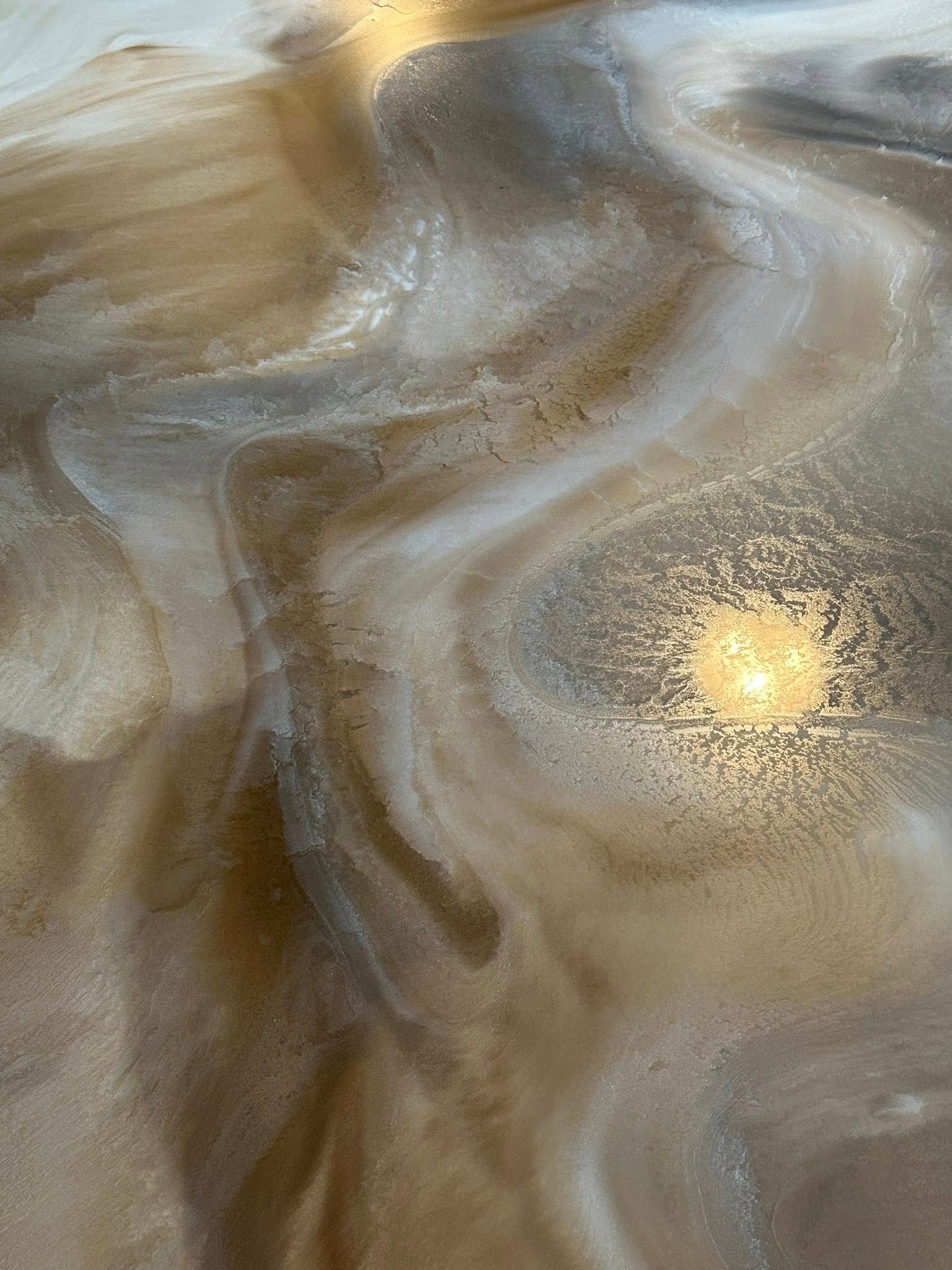 Swirling metallic epoxy floor, with gold, silver, and brown hues.