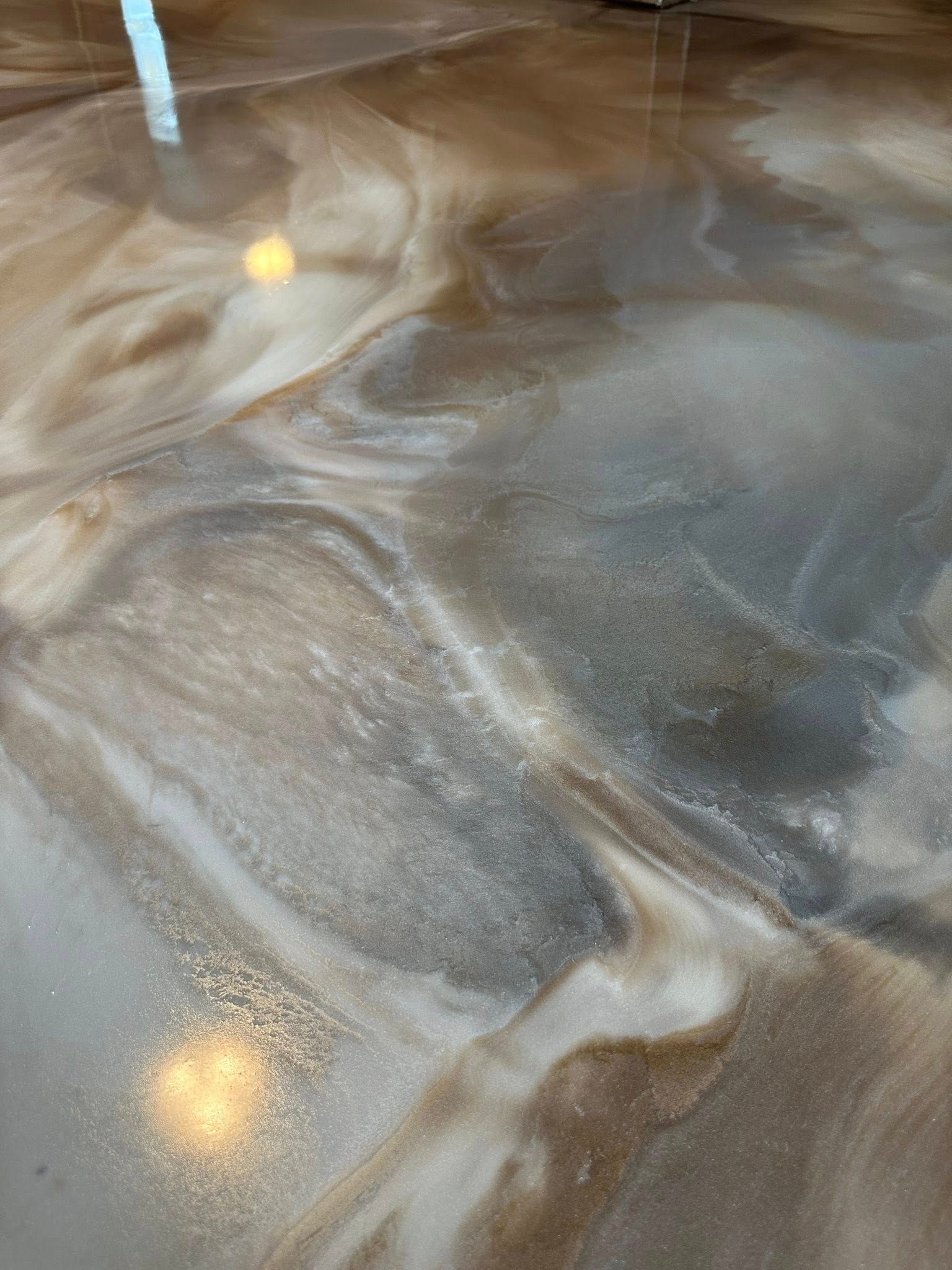 Metallic epoxy floor with swirled, brown, white, and gray patterns.