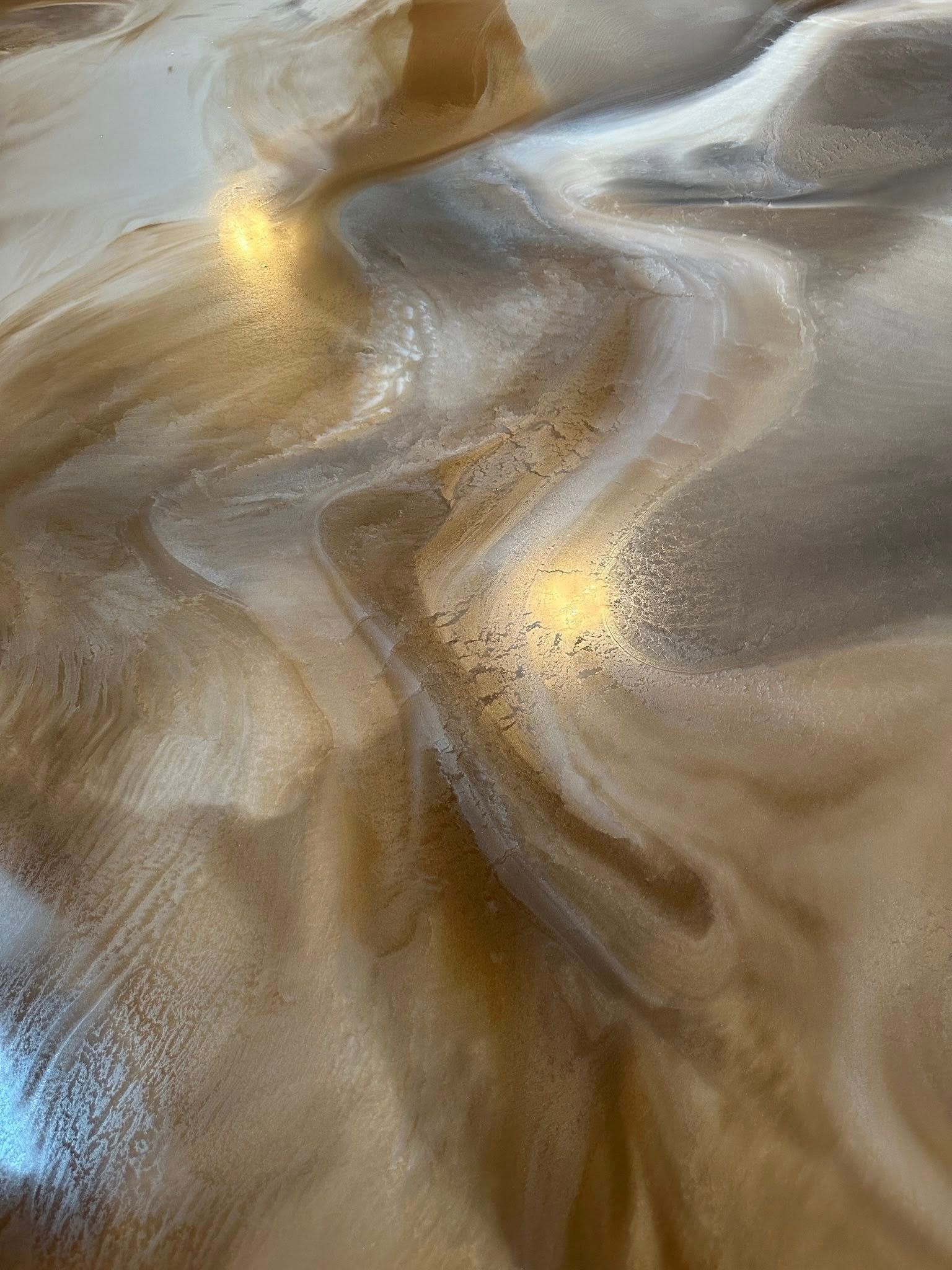 Swirling metallic epoxy floor in shades of gold, brown, and silver.