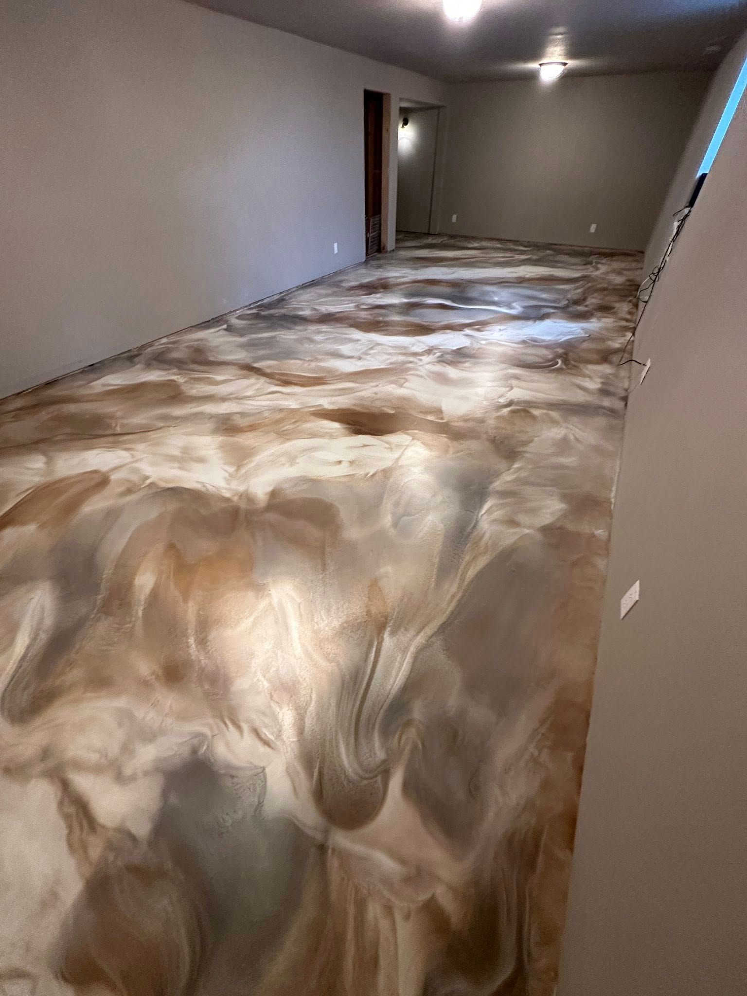 Finished metallic epoxy flooring in a long, empty room; tan, gold, and grey swirls.