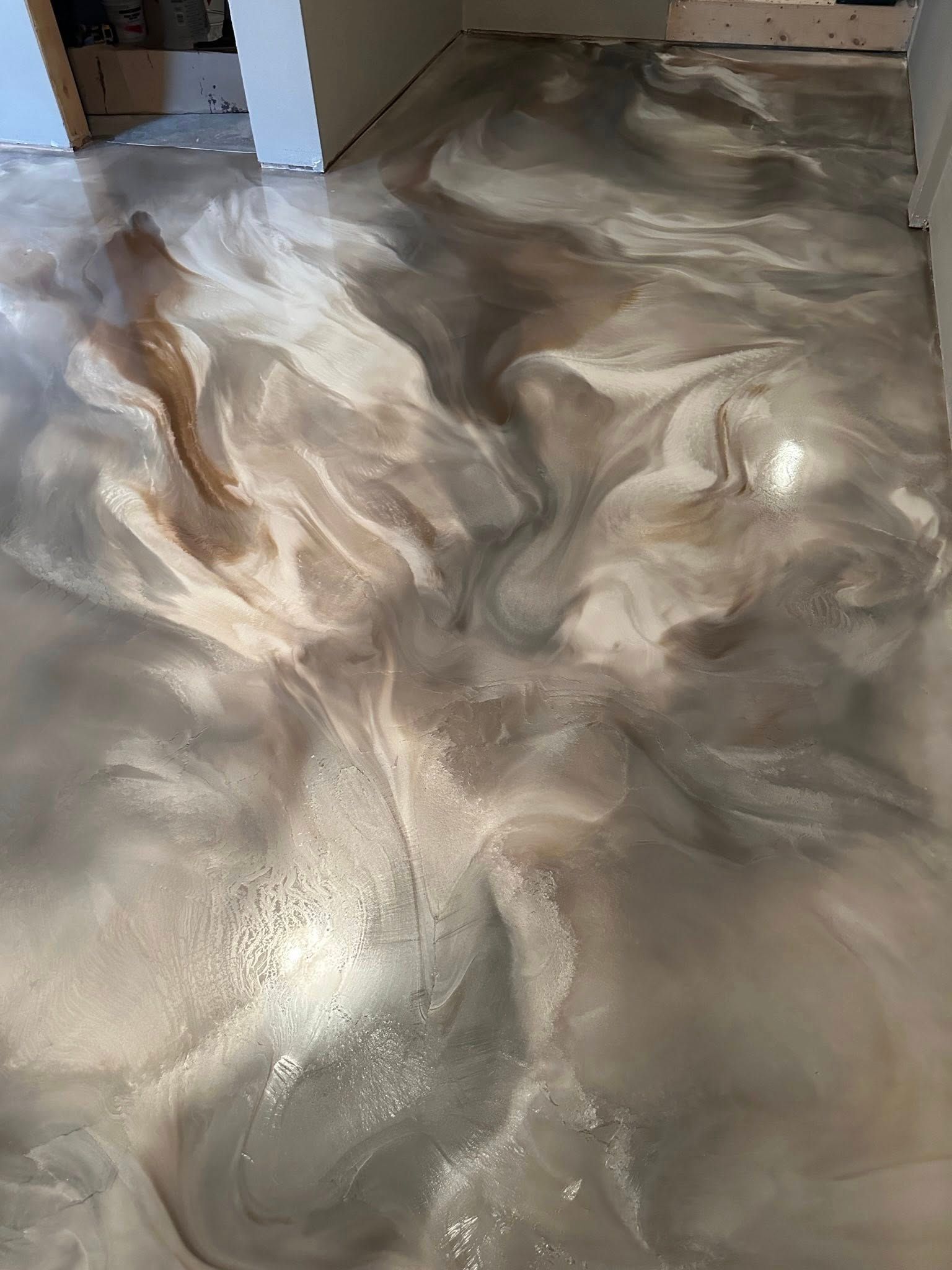 Metallic epoxy floor with swirled silver, white, and bronze tones.