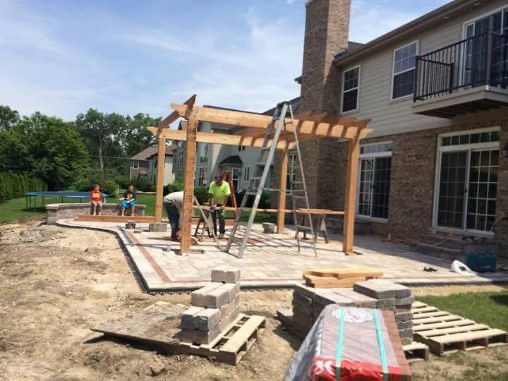 A pergola is being built in the backyard of a house.