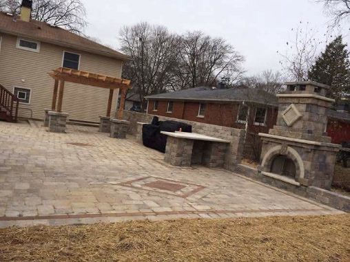A patio with a fireplace and a table in front of a house.
