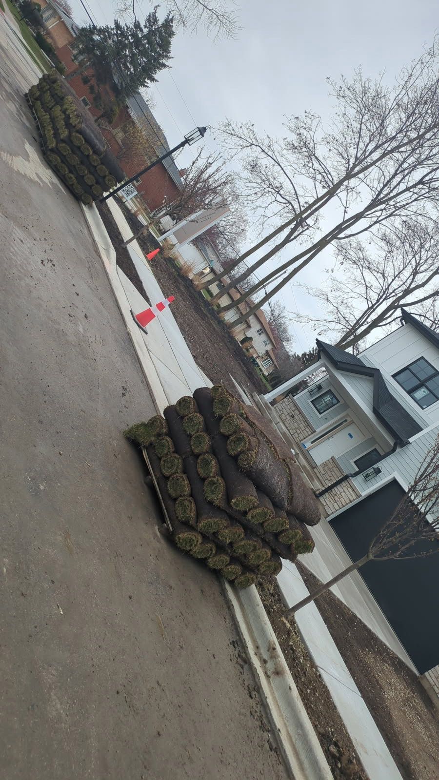 A pile of turf is sitting on the side of the road next to a house.