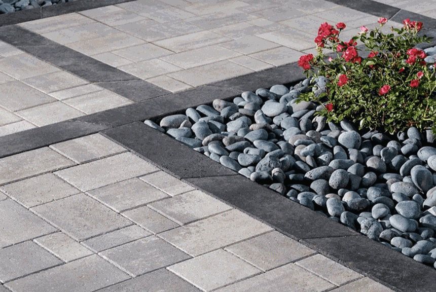 A brick walkway with a planter filled with rocks and flowers.