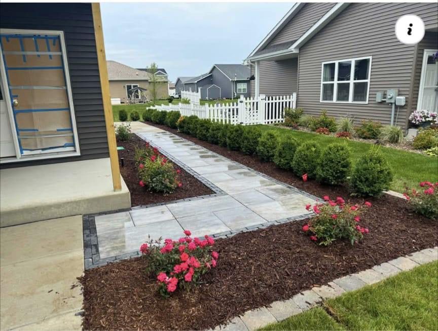A walkway leading to a house with a white picket fence