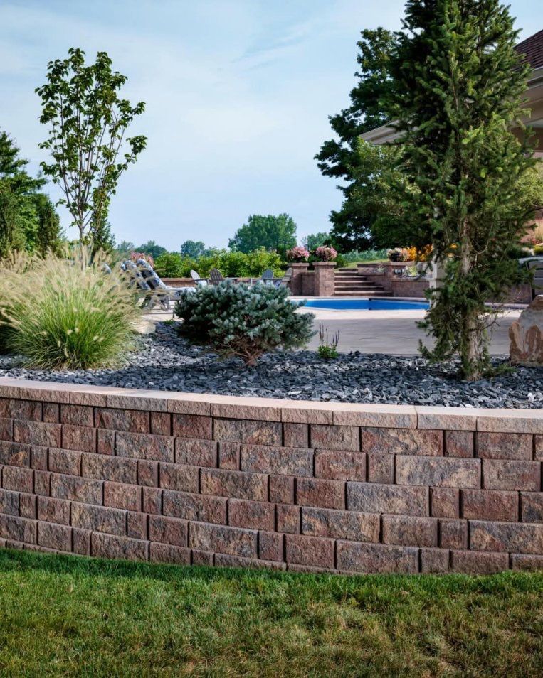 A brick wall surrounds a swimming pool in a backyard