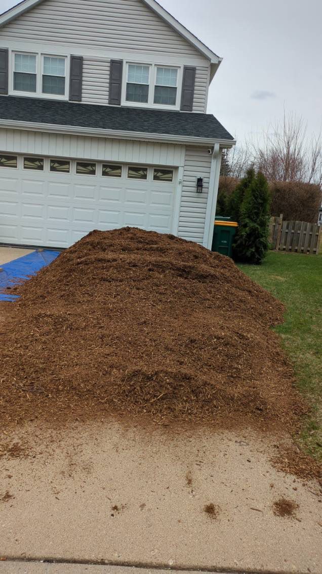 A pile of mulch is sitting in front of a house.