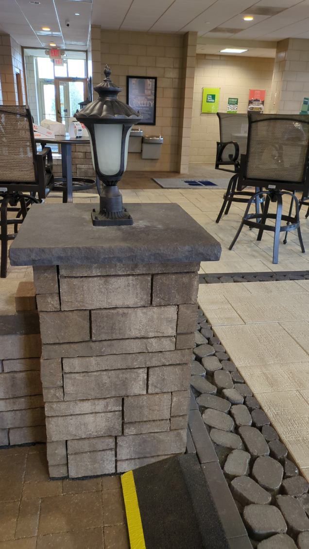 A brick pillar with a lamp on top of it in a room with chairs.