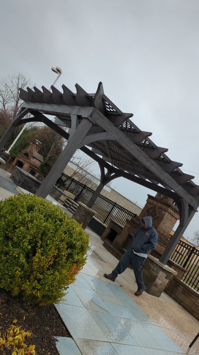 A man is standing under a pergola on a cloudy day.