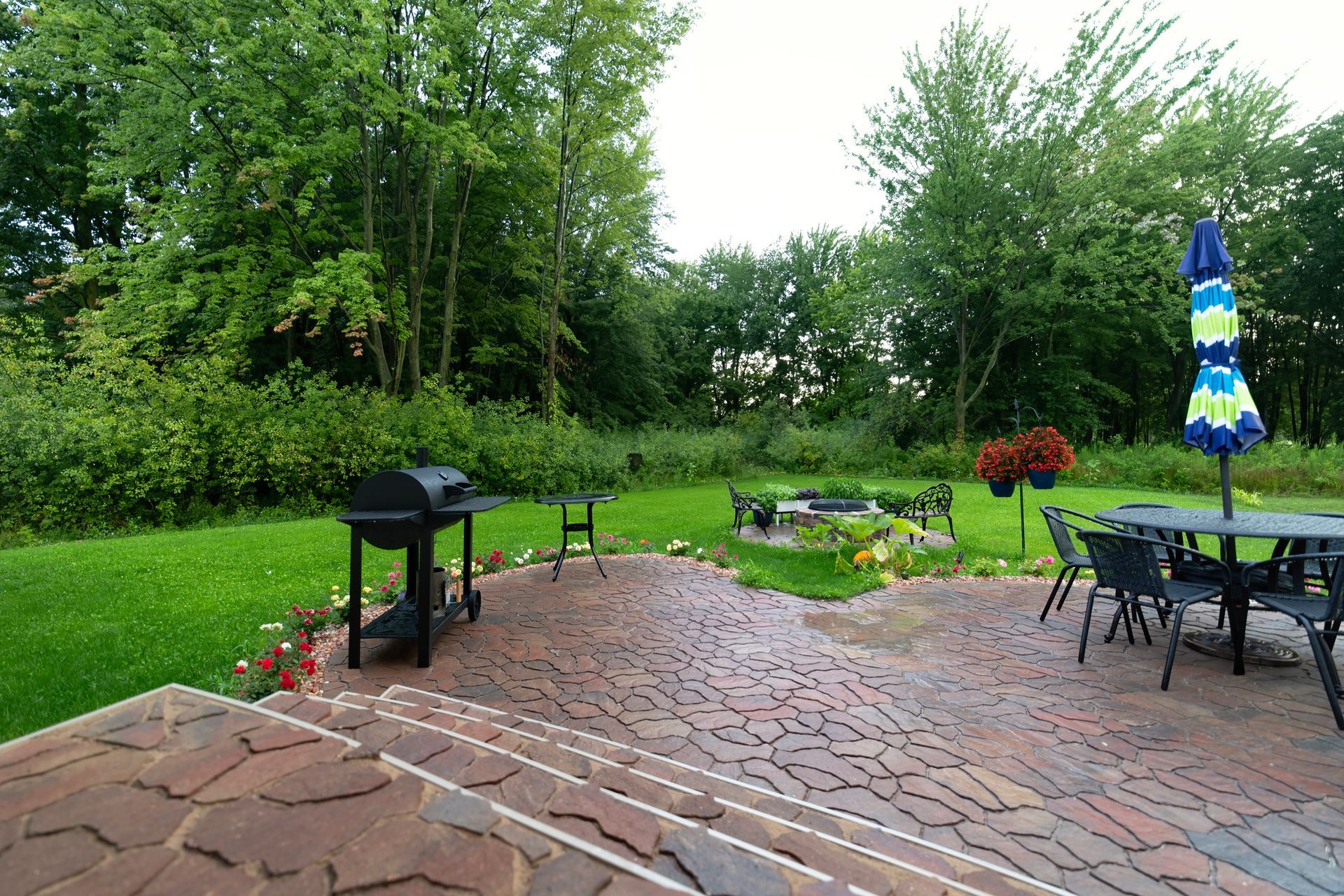 A patio with a grill , table and chairs and an umbrella