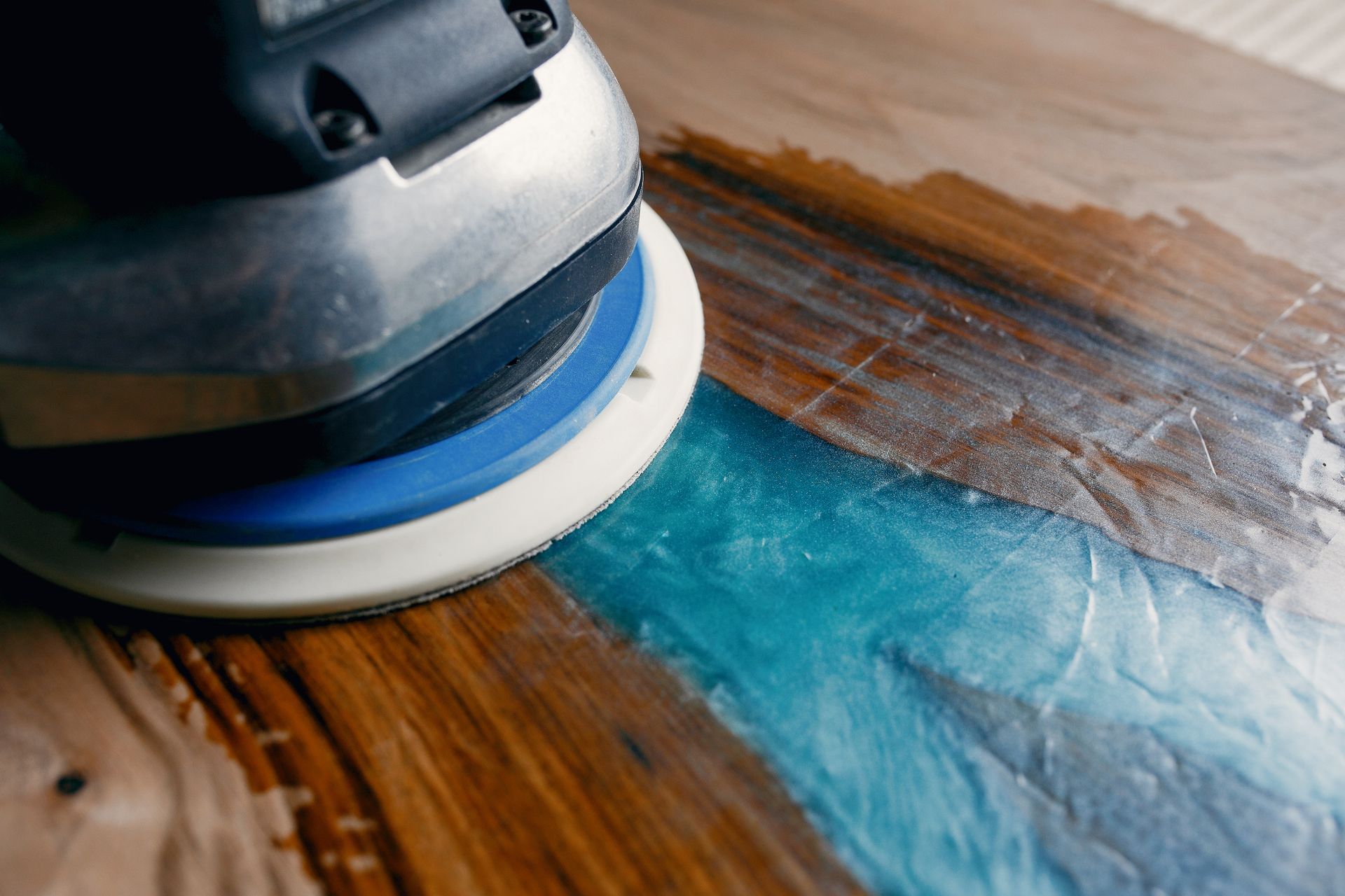 A person is sanding a piece of wood with a sander.