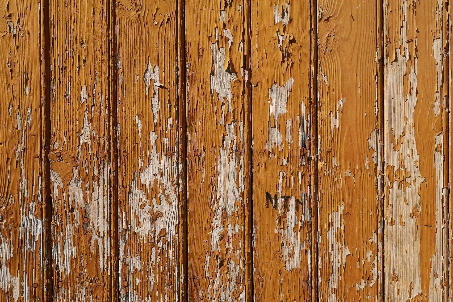 Close-up of wood floor damage with peeling paint and surface wear.