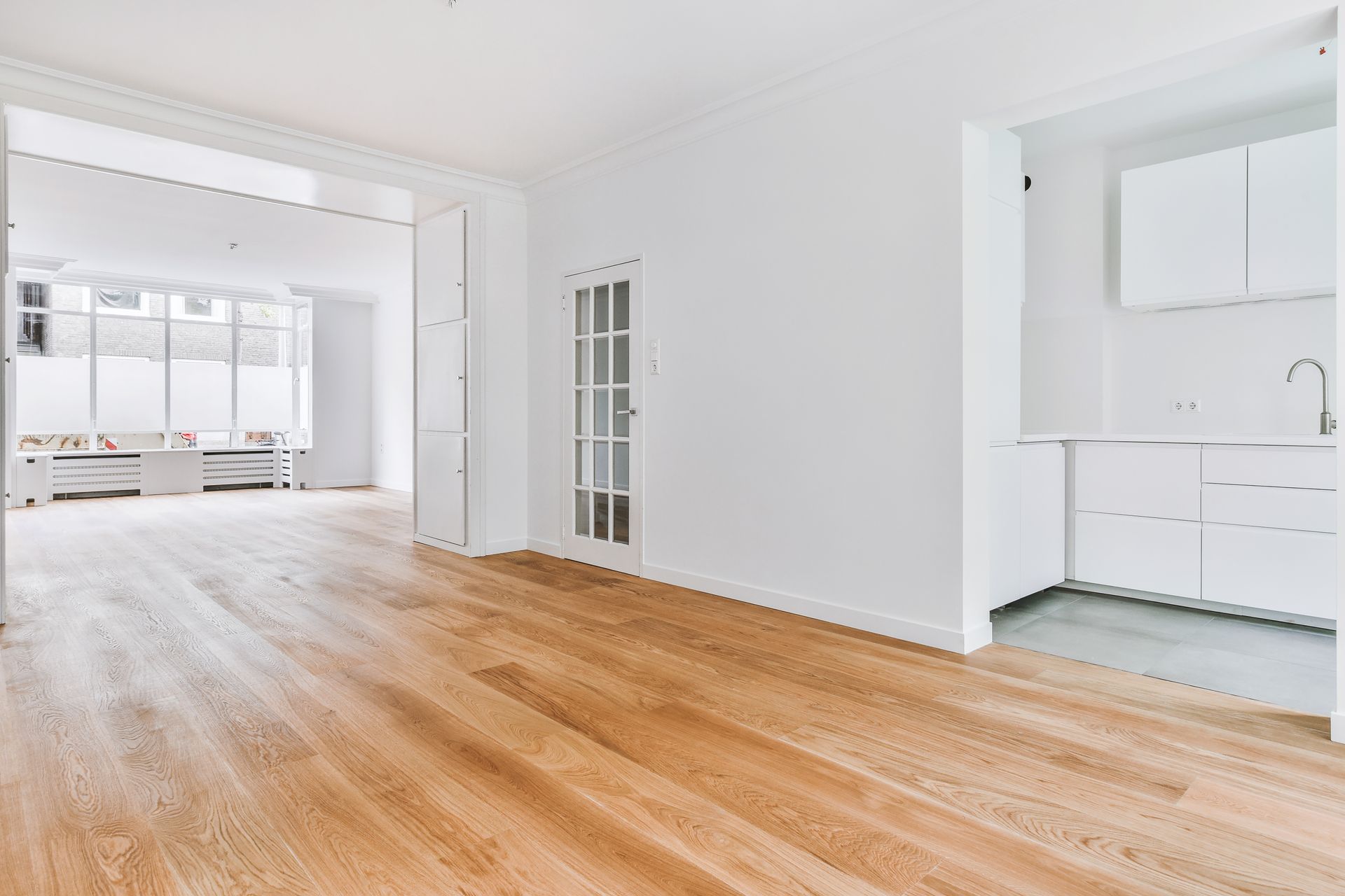 An empty room with hardwood floors and white walls