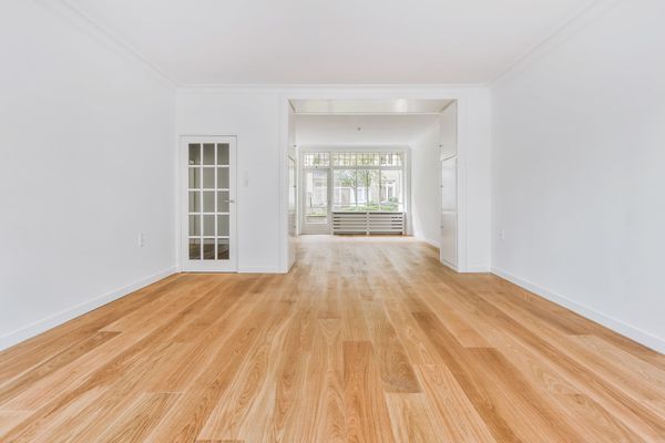 An empty living room with hardwood floors and white walls.