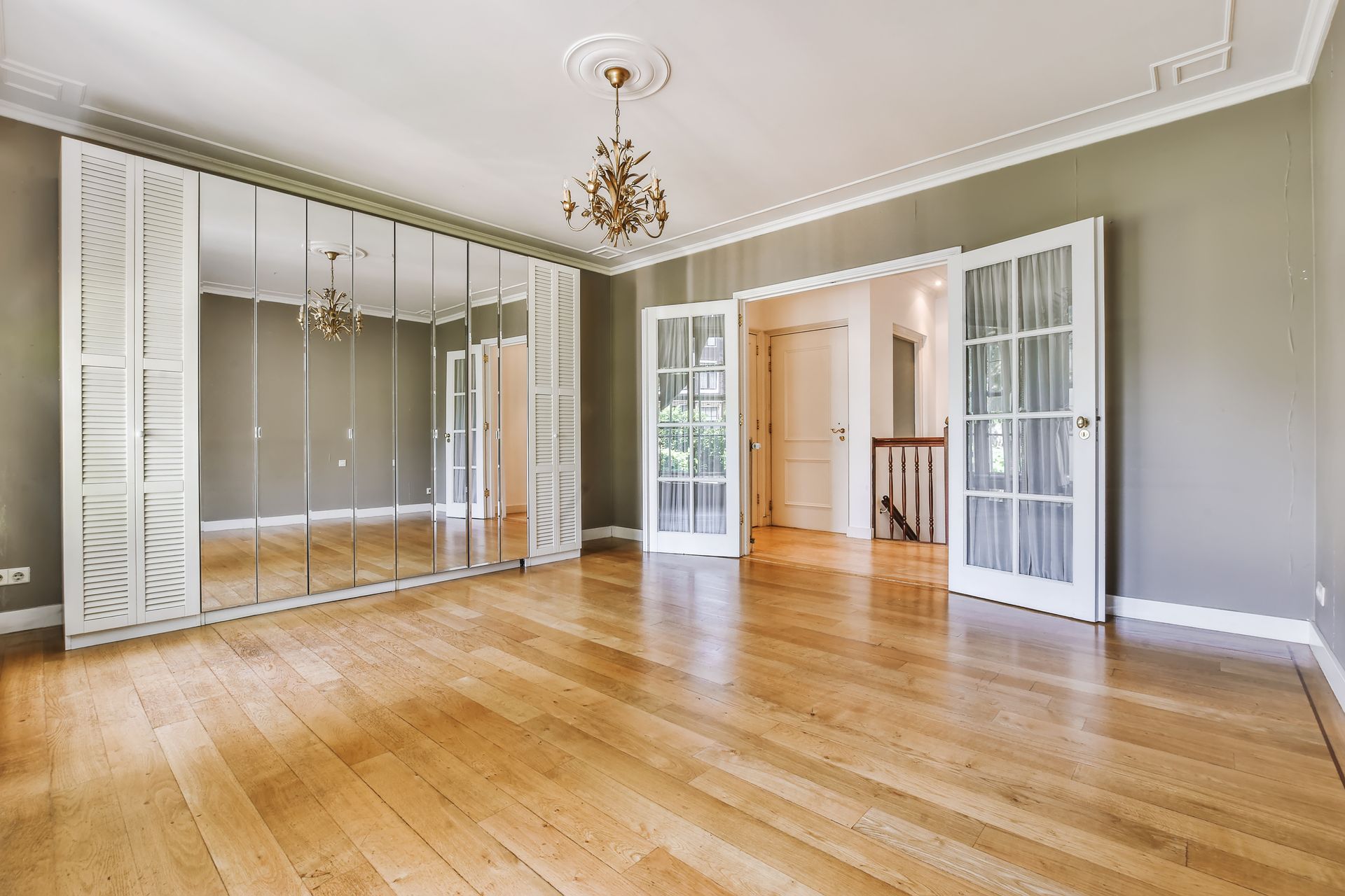 A large empty room with hardwood floors and a chandelier