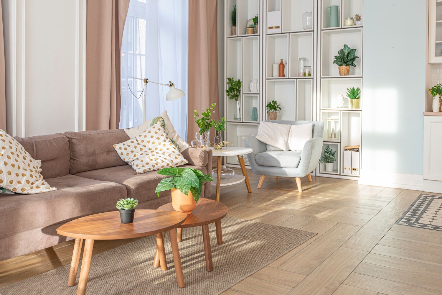 A living room with a couch , chair , tables and shelves.