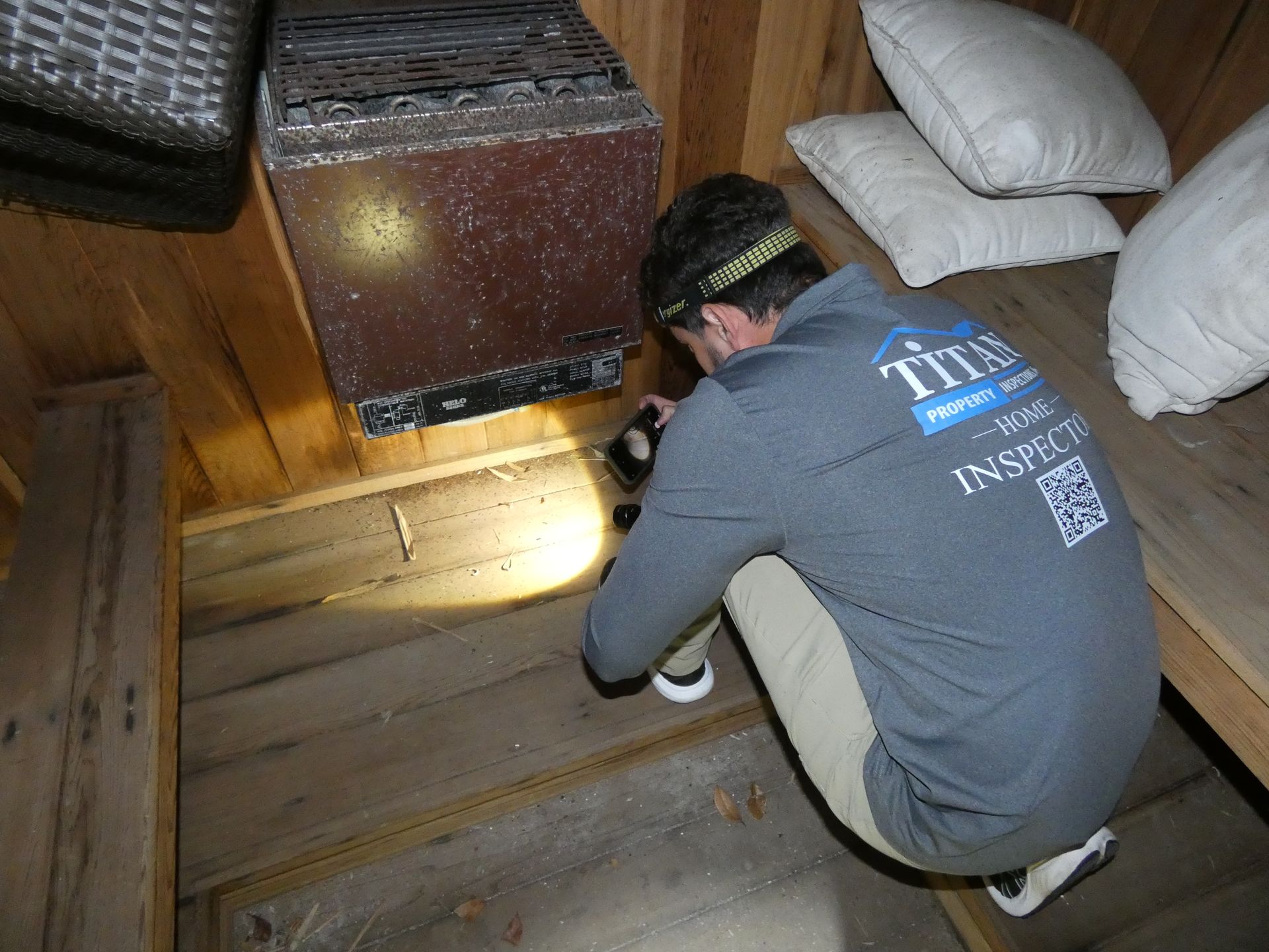 Persona inspeccionando una estructura de madera con una linterna.