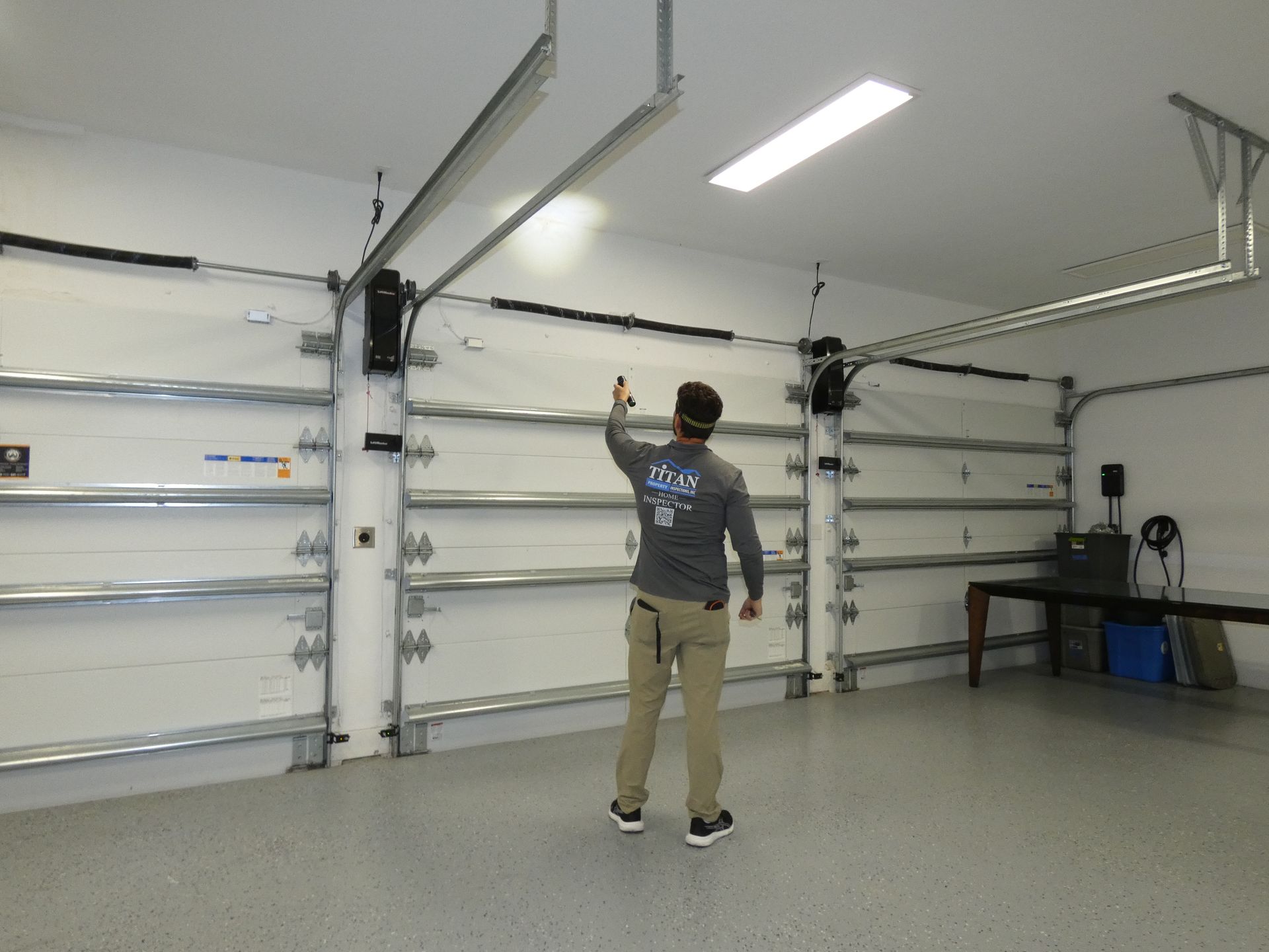 Persona en un garaje señalando hacia arriba, cerca de la puerta. El garaje tiene un interior blanco y suelo de epoxi.
