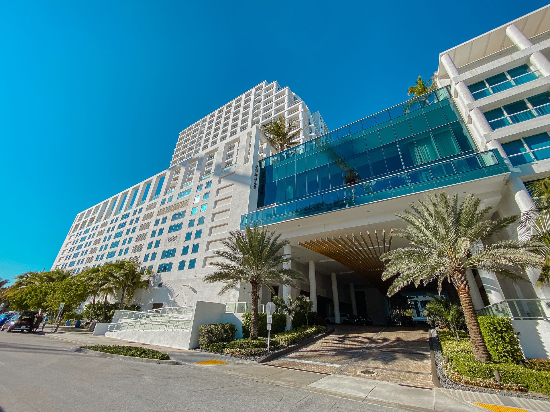 Edificio de hotel moderno de color blanco con detalles de vidrio bajo un cielo azul brillante.