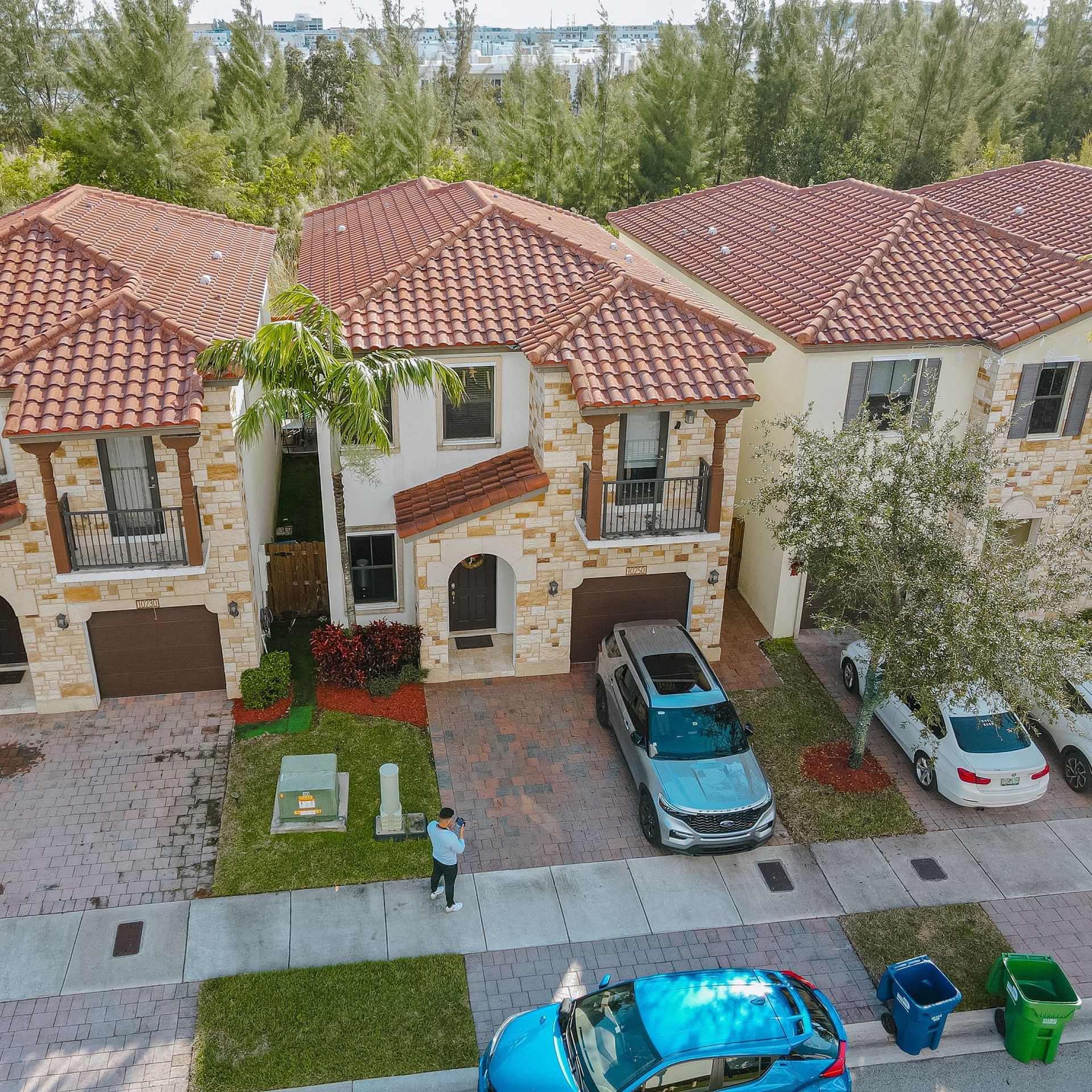 Hilera de casas adosadas con techos de tejas y revestimientos de color tostado; automóviles estacionados en las entradas y en la calle.