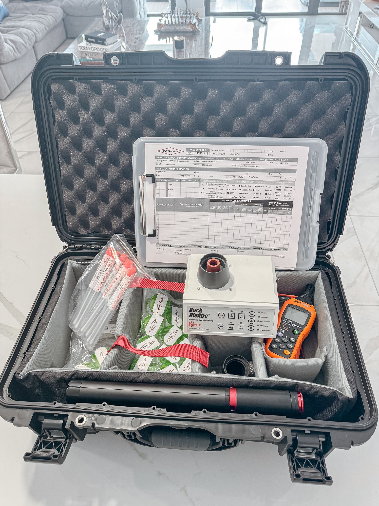 Estuche negro abierto con equipo para pruebas; documentos, medidor, tubos y otros componentes.