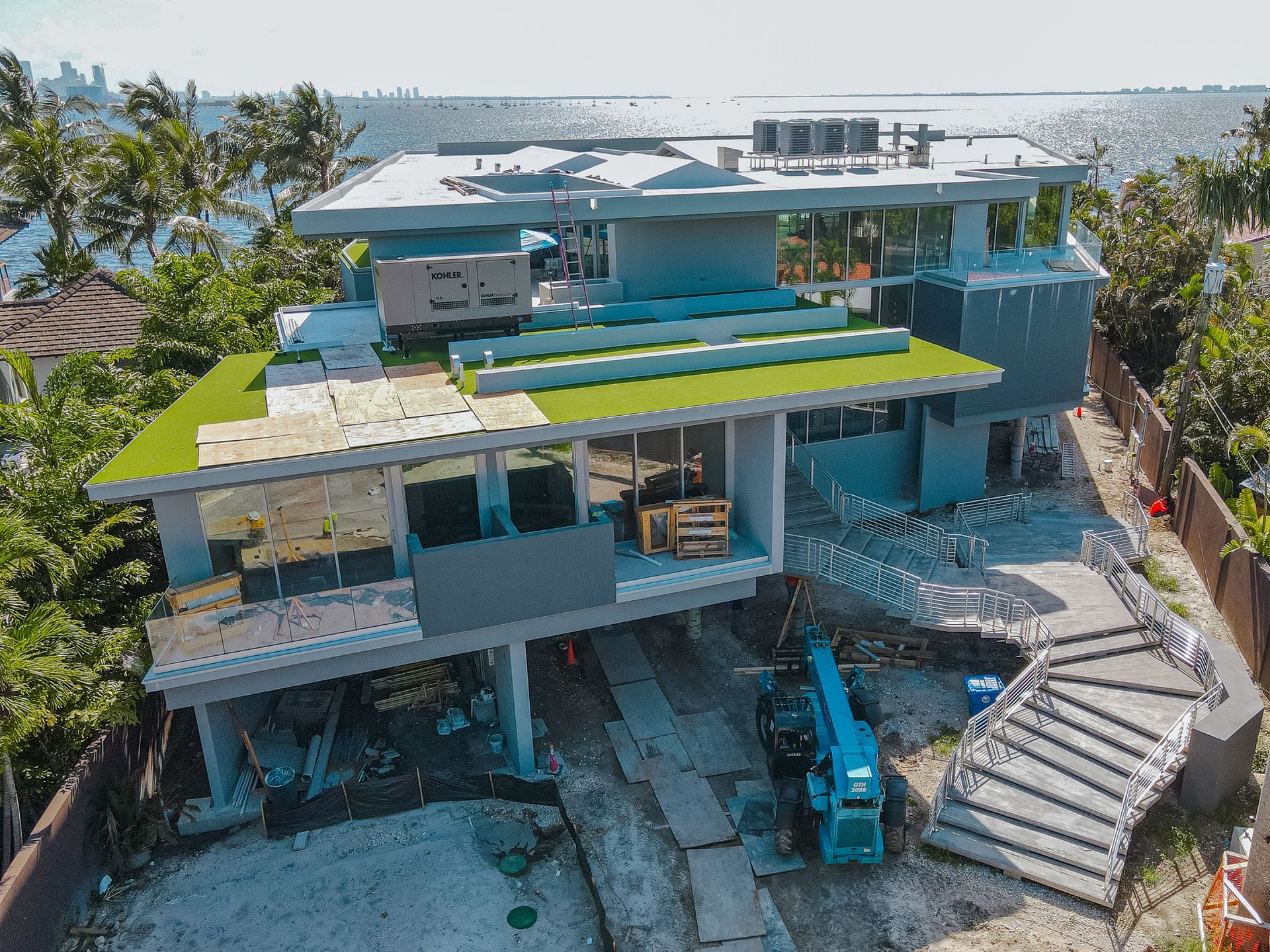 Casa moderna en construcción con techo verde, paredes parciales de vidrio y vista al mar.