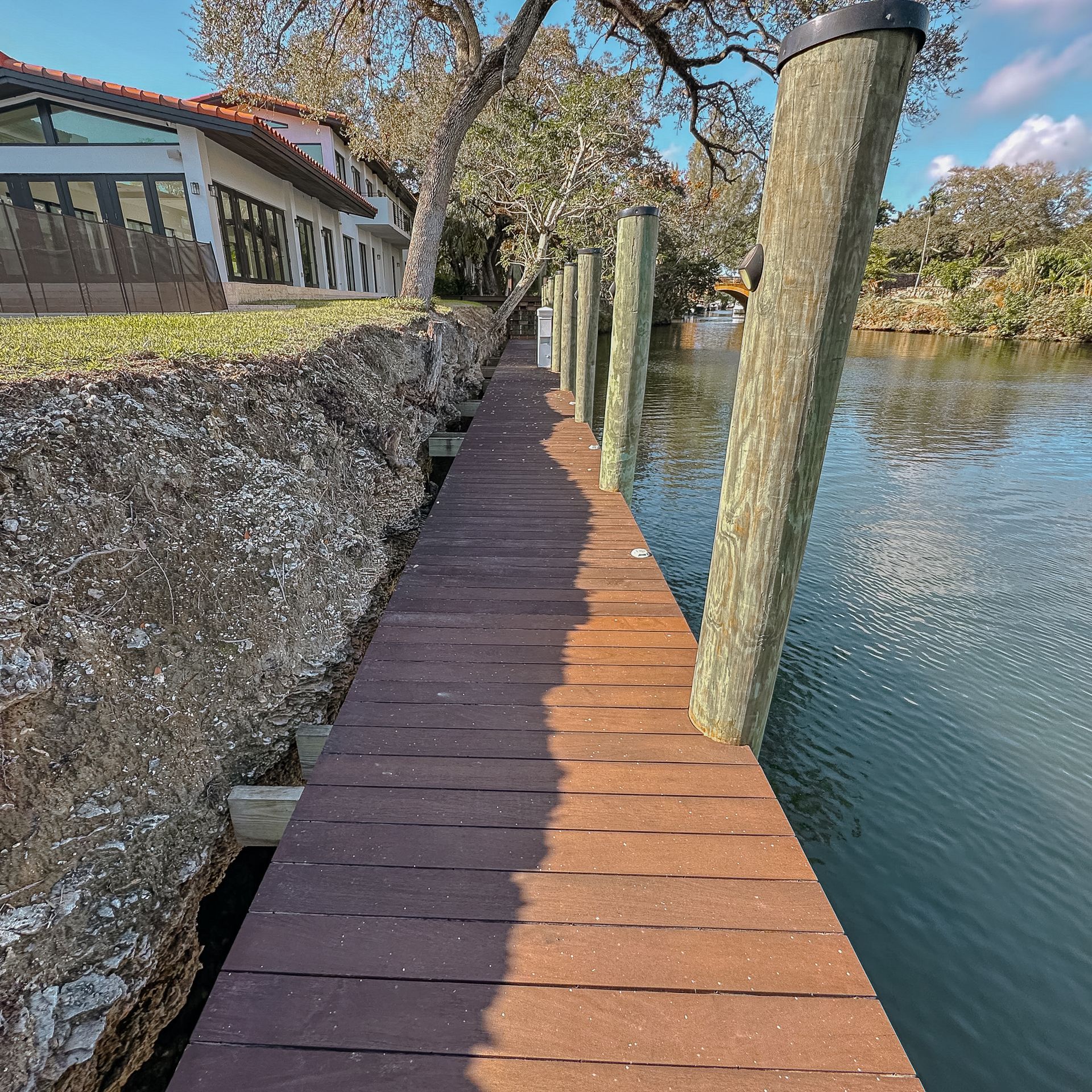 Muelle de madera junto a la costa rocosa, que conduce a una casa en un canal.