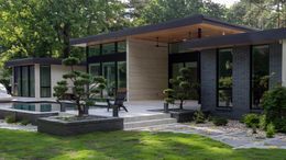 Modern house with large glass windows, wood roof, and landscaped garden