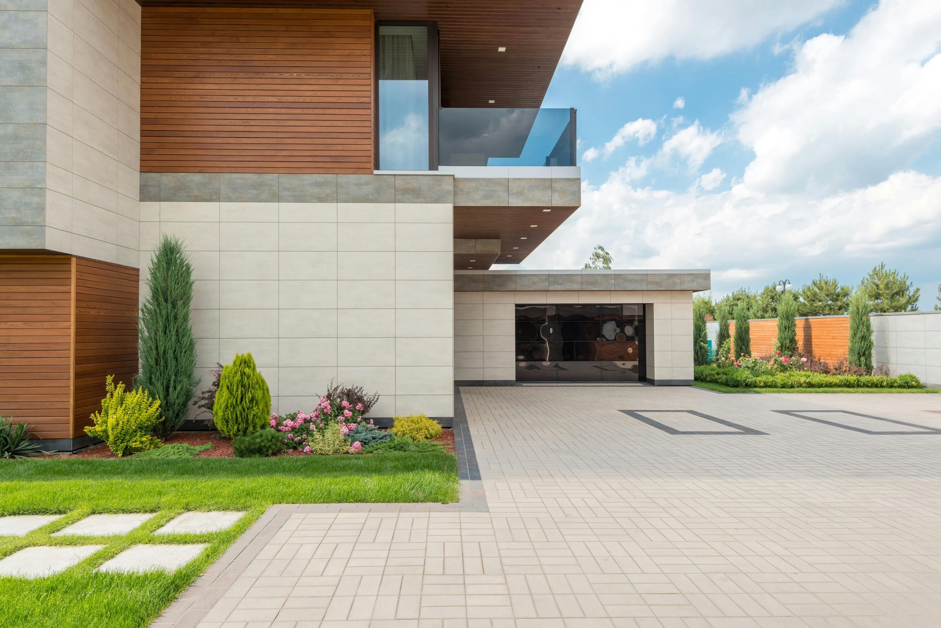 Modern luxury home exterior with driveway, garage, wood siding, and landscaped front yard