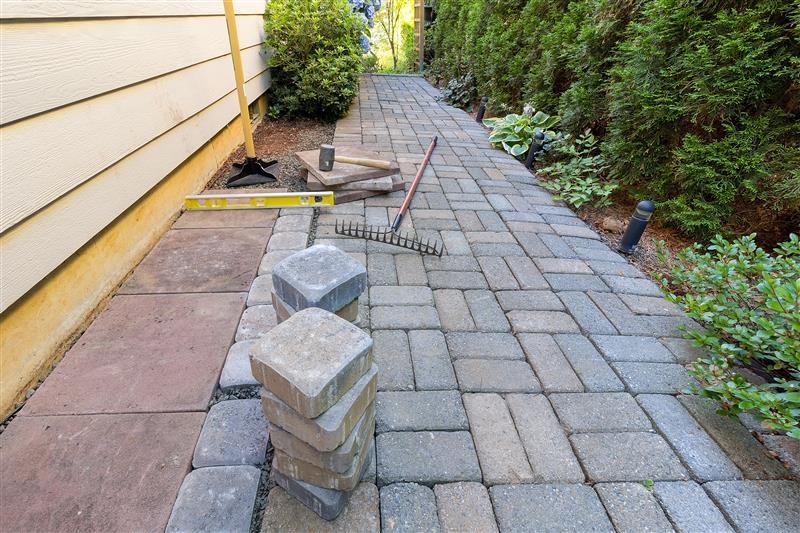 Pathway under construction with pavers, rake, and tools.