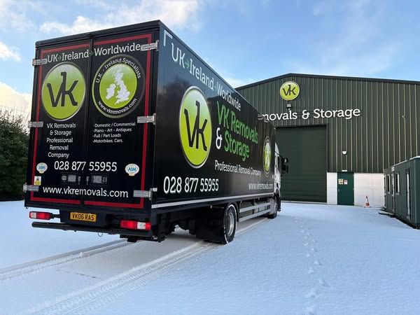 A white and black semi-truck with logos on the side and front parked on a snow-covered surface.