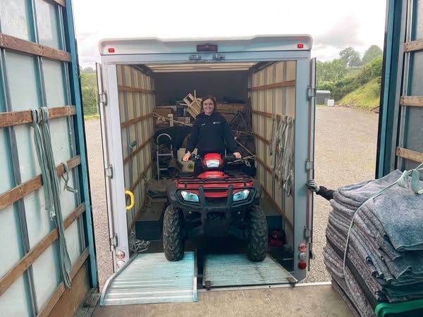 Two white moving vans parked in front of a large brick house.