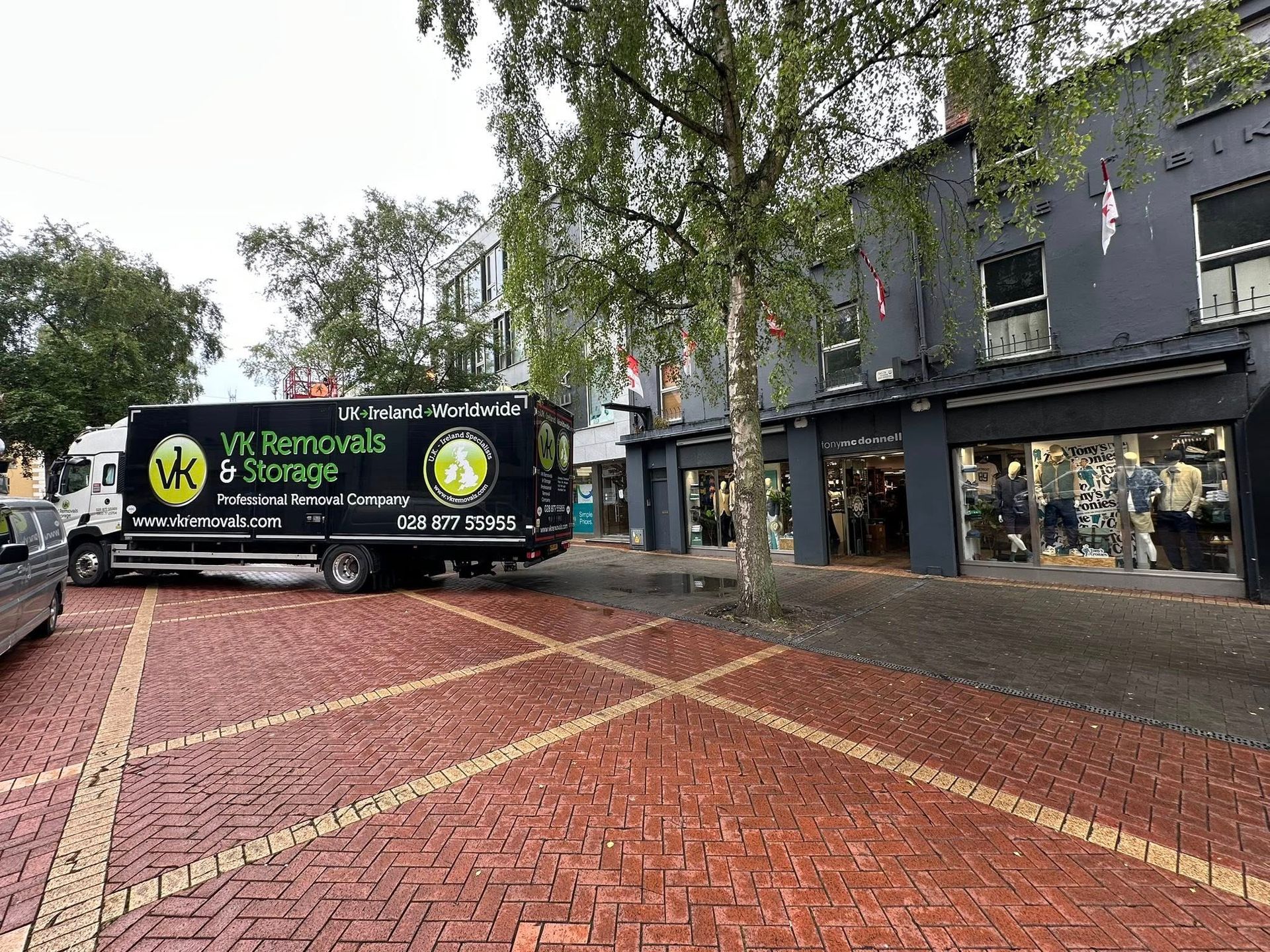 A truck is parked in front of a building on a brick sidewalk.