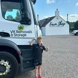 Boy by a VK Removals truck, thumbs up, near a Farm Shop.