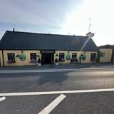 Yellow building with dark roof, road in front. Green apple decorations on wall.