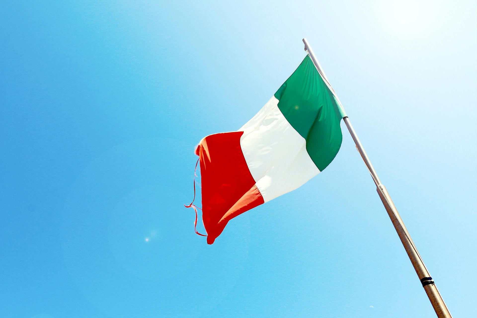 Italian flag waving against a bright blue sky.