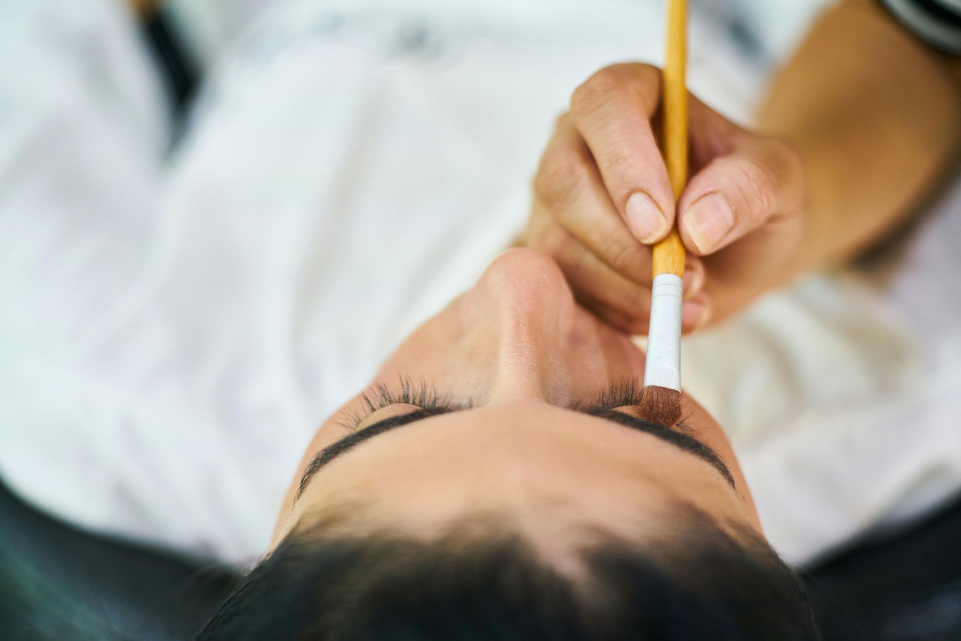 A woman is getting her eyebrows painted by a makeup artist.