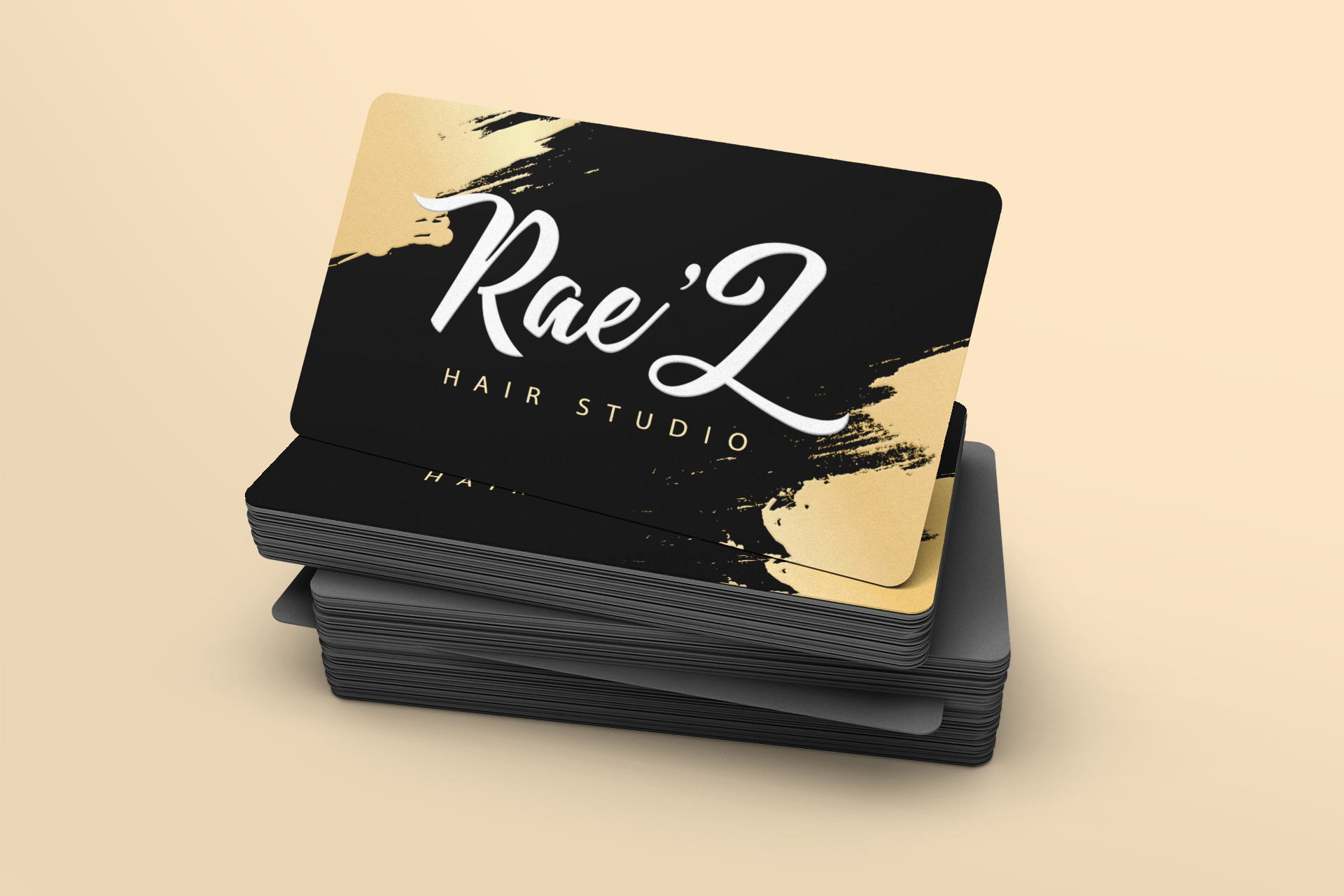 A black and gold business card for a hair studio is stacked on top of each other.