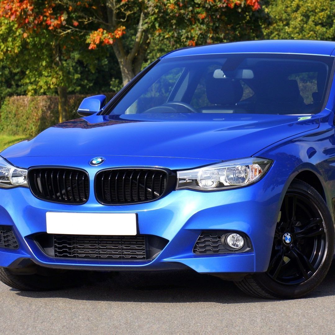 A blue bmw is parked on the side of the road