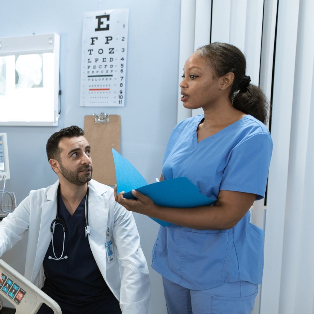 A nurse is talking to a doctor in a hospital room