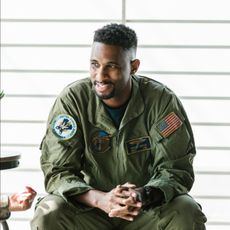 A man in a military uniform is sitting down with his hands folded