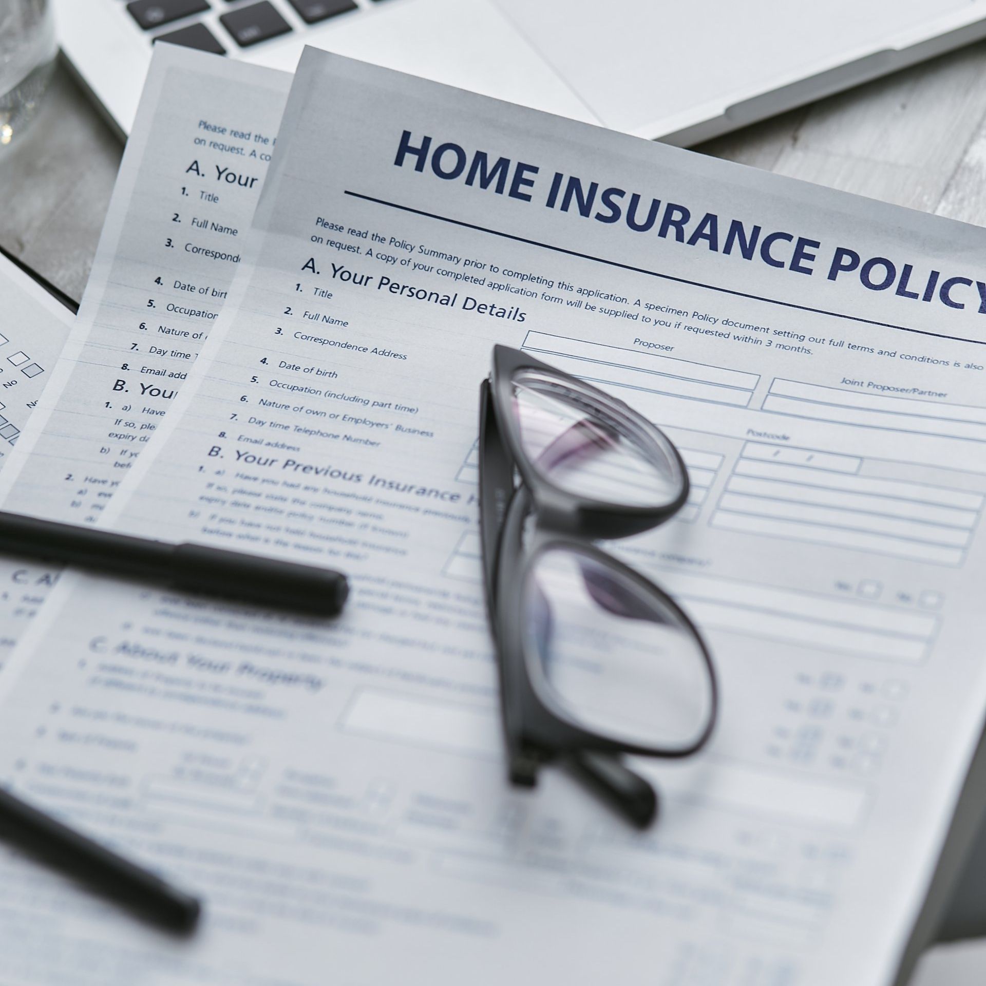 A pair of glasses sitting on top of a home insurance policy