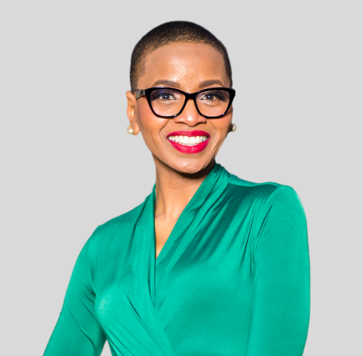 A woman wearing glasses and a green shirt is smiling.