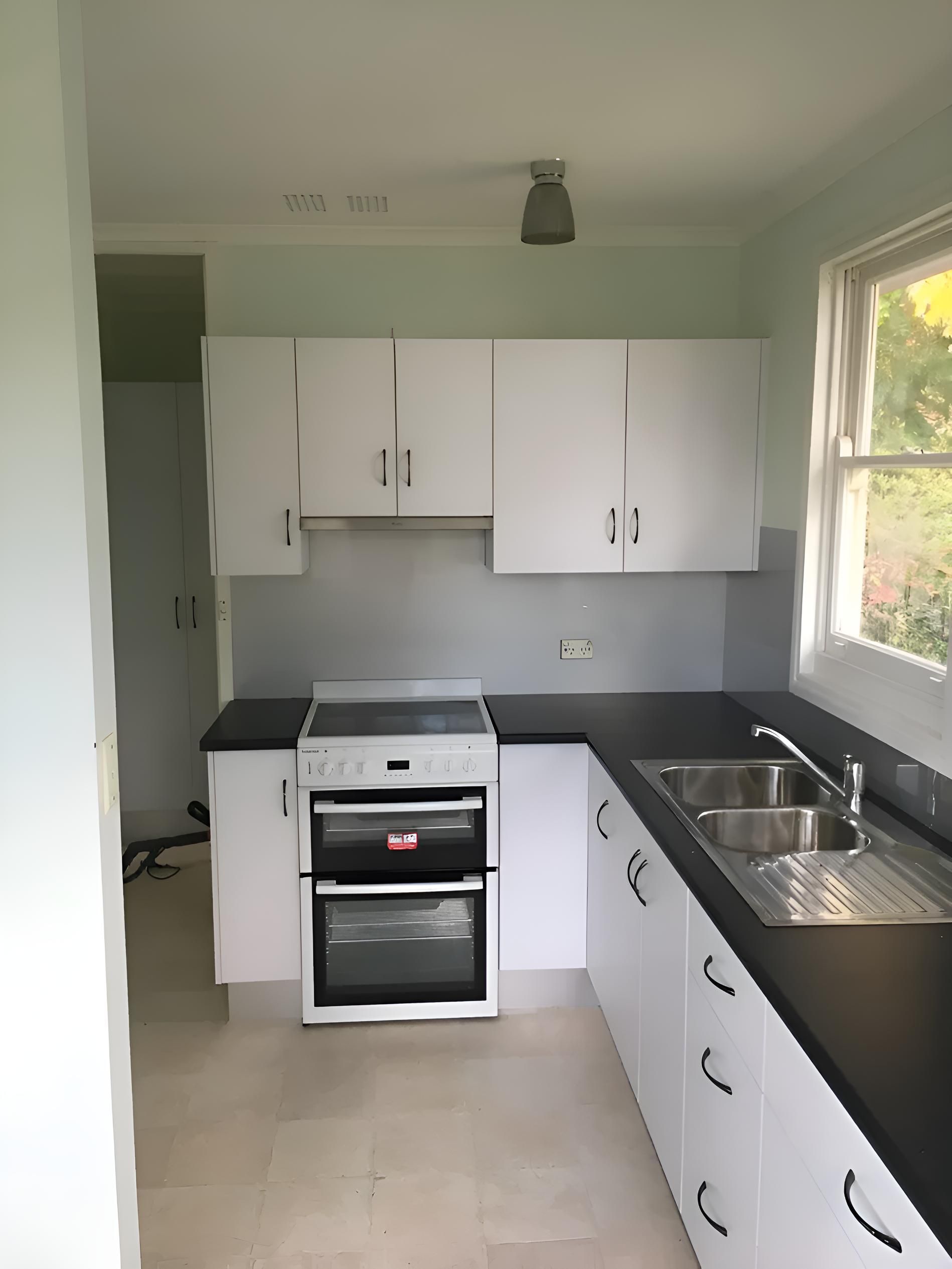 An Empty Kitchen With White Cabinets And Black Counter Tops — Hey Presto Kitchens & Renovations in Armidale, NSW