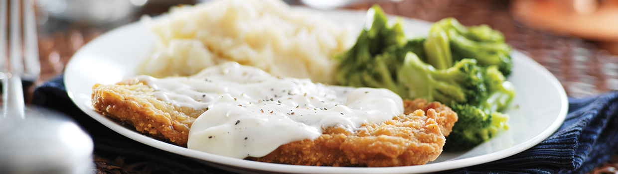 A white plate topped with chicken fried steak , mashed potatoes and broccoli.