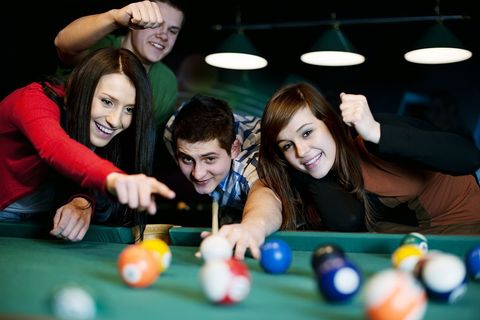 A group of young people are playing pool together.
