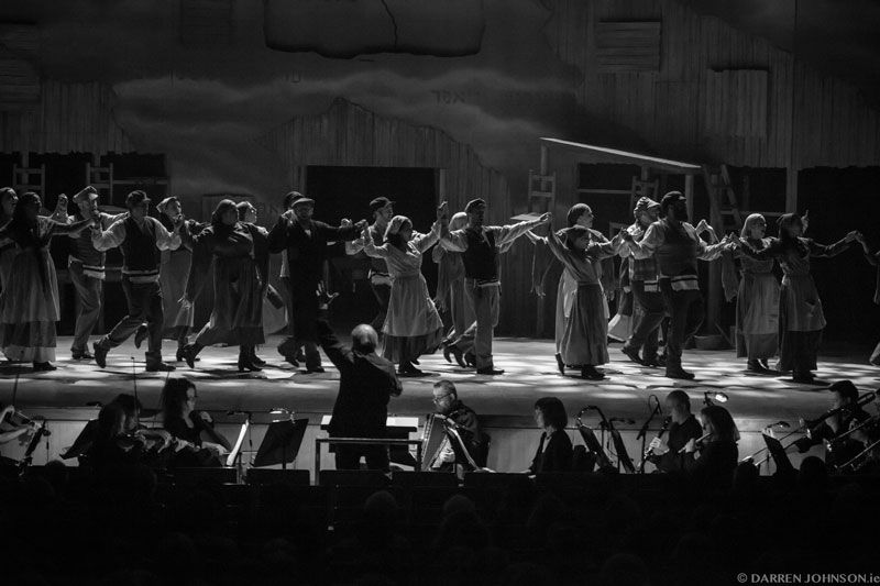 A black and white photo of a group of people dancing on a stage.
