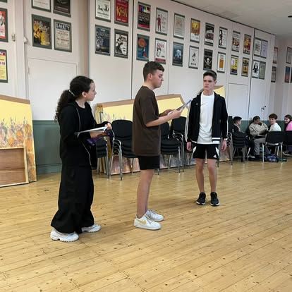 A group of people are standing on a wooden floor in a room.